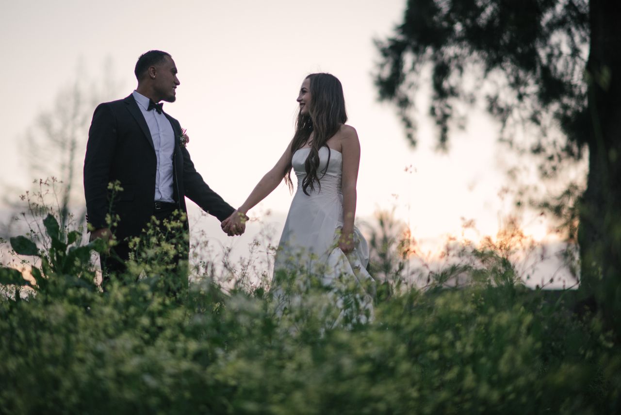 Couple holding hands in wildflowers at golden hour