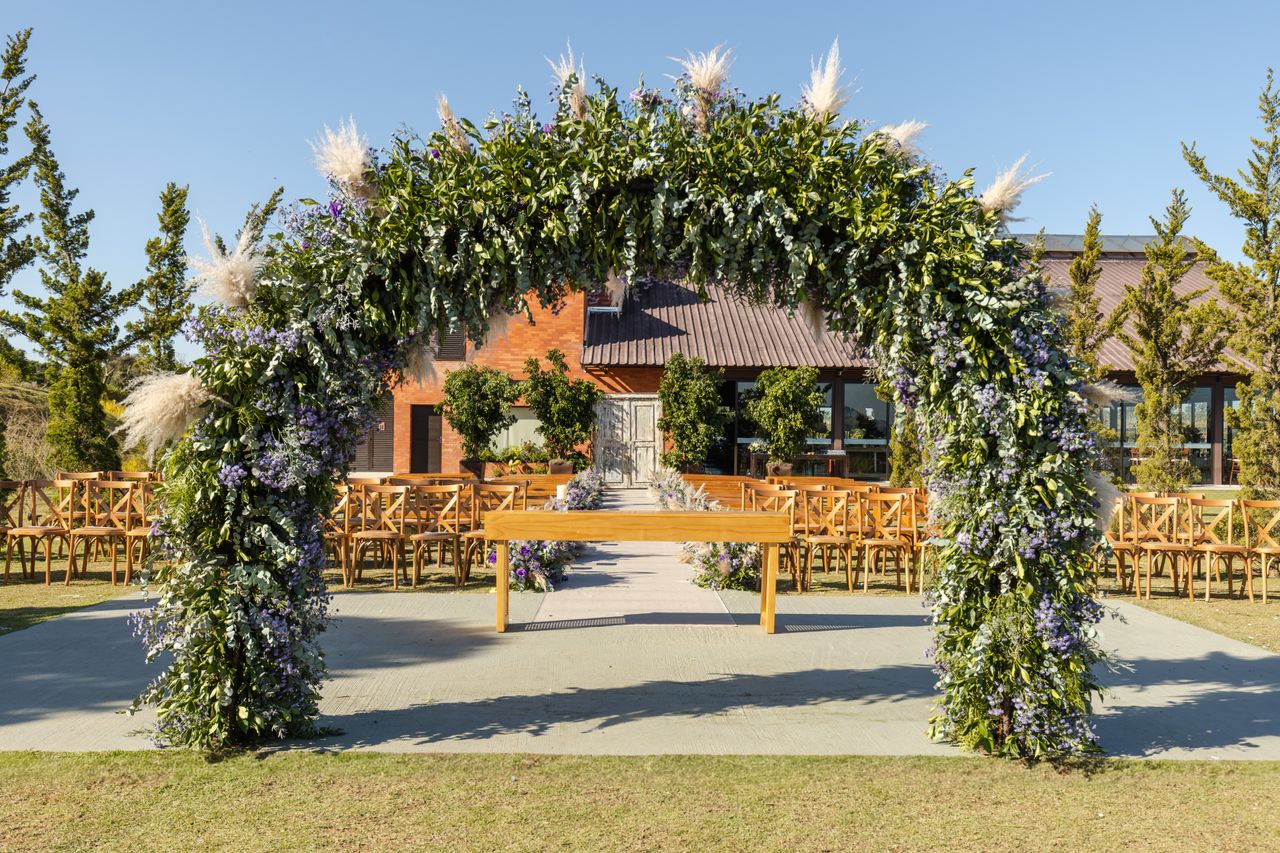 Outdoor ceremony arch with floral archway and wooden chairs